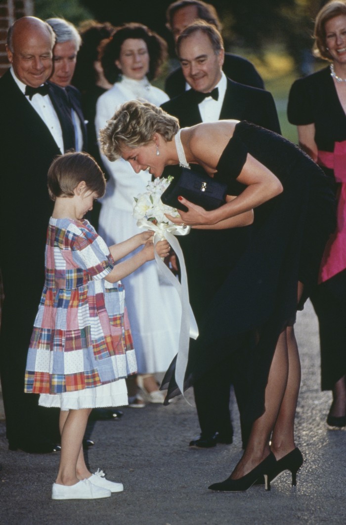 Princess Diana (1961 - 1997) receives a bouquet from a young girl, as she arrives for a gala event at the Serpentine Gallery, London, 29th June 1994. The princess is wearing a black gown by Christina Stambolian. (Photo by Tim Graham Photo Library via Getty Images)