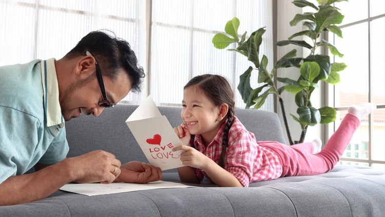 Ilustrasi Kado di Hari Ayah Happy Father's Day, adorable cute little girl with young man dad lying on sofa in living room, making handmade greeting card for calibration. Happy family daughter and father spending time together.