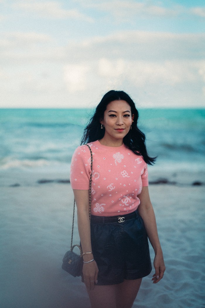 Arden Cho dari serial Netflix Partner Track bergaya feminin dan kasual lewat kaus pink dan celana pendek serta tambahan belt. Foto: Courtesy of Chanel