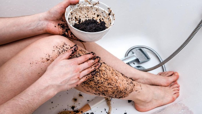 Woman cleans her feet with coffee scrub. Health and spa theme
