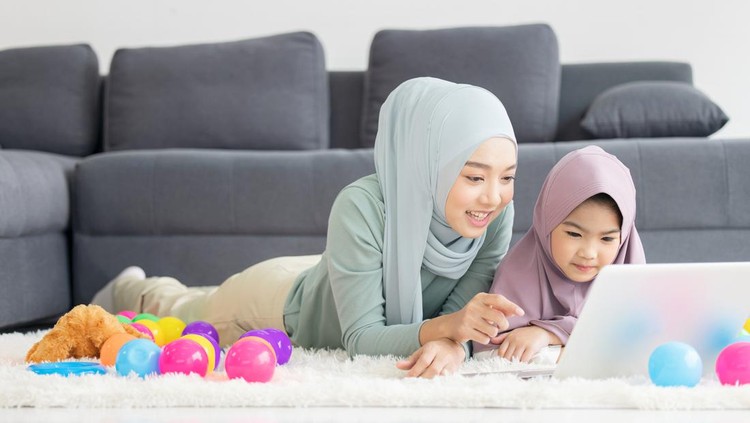 Muslim Mother working with laptop and Cute little baby playing toys in living room at home.