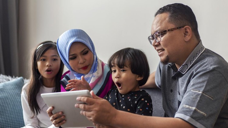 happy Asian family feeling excited while watching movie from digital tablet at home