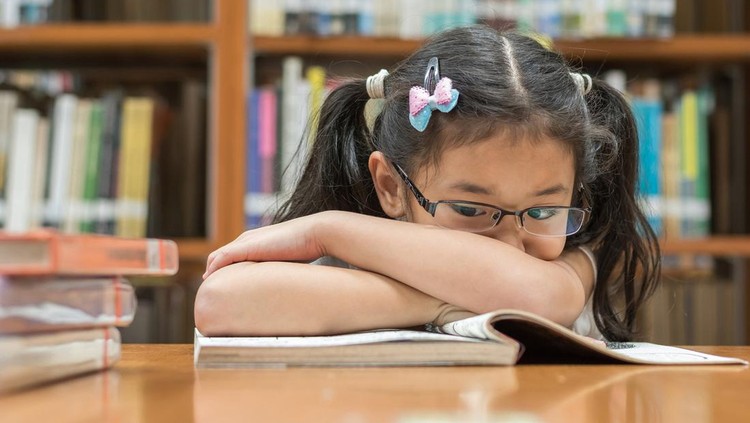 Ilustrasi Cara Mencegah Rabun Jauh pada Anak Unsuccessful educational system concept with Asian child girl student getting bored reading book in school classroom library