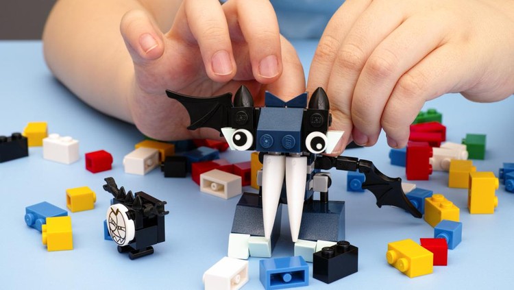 Ilustrasi Kegiatan Bermain Anak Tambov, Russian Federation - March 08, 2015: Child playing with Lego Mixel Vampos on blue table. There are some Lego bricks on table. Studio shot.