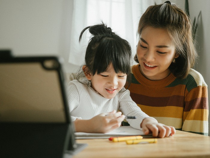 Asian mother and  daughter doing homework at home. The school has been closed during coronavirus outbreak and the classes have moved to e-learning platform.