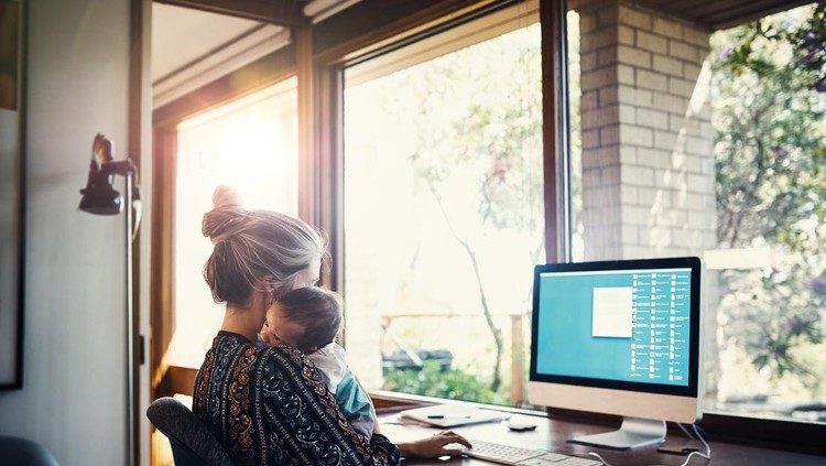 Asian young woman holding her baby on hands while making notes at the table she working at home