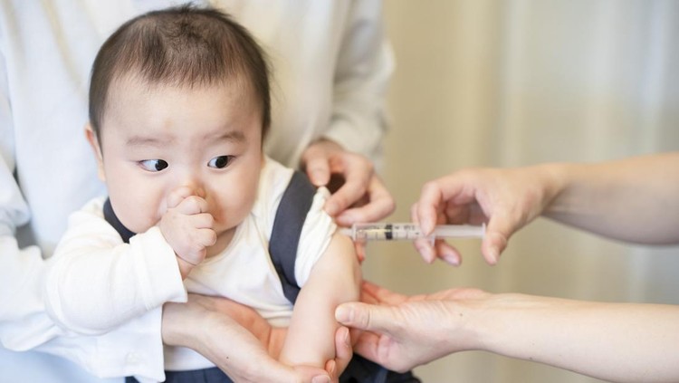 A baby who is vaccinated while being held by her mother