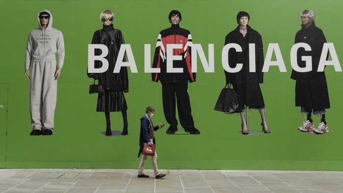 People interact with large scale action figures wearing fashionable clothing against a huge green hoarding which covers the Balenciaga store during a refit in the upmarket area on Bond Street on 25th May 2021 in London, United Kingdom. These high end brands are seen next to each other on a very ordinary wall. Bond Street is one of the principal streets in the West End shopping district and is very upmarket. It has been a fashionable shopping street since the 18th century. The rich and wealthy shop here mostly for high end fashion and jewellery. (photo by Mike Kemp/In Pictures via Getty Images)
