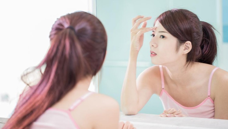 woman look mirror with acne problem in the bath room