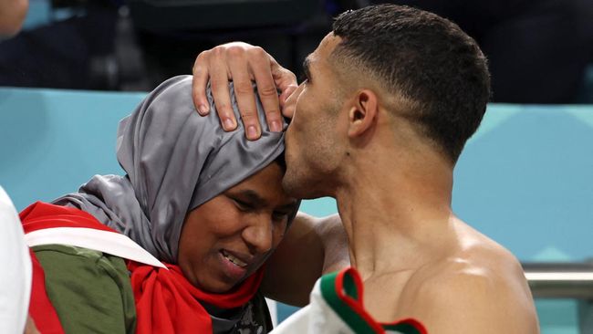 Achraf Hakimi Cium Kening Ibu Usai Maroko Hajar Belgia Pemain Maroko Achraf Hakimi berlari ke tribune penonton setelah menang atas Belgia di Piala Dunia 2022 lalu kecup kening sang ibu.