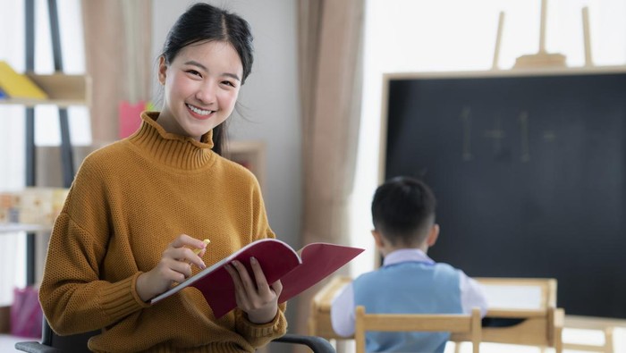 Asian teacher At preschool Helping Children in Class in class room