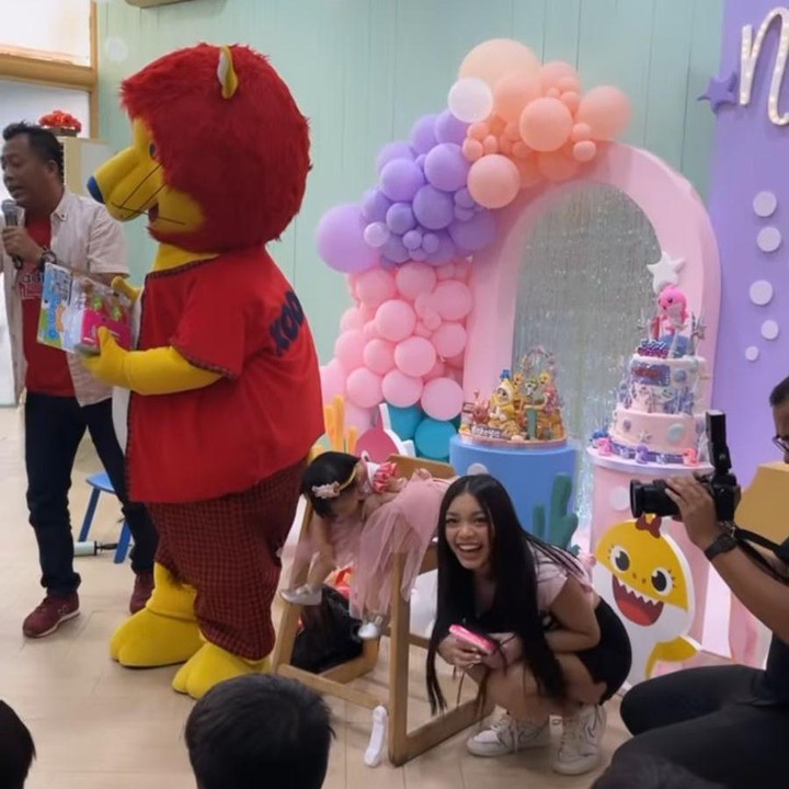 <p>Nakeya yang mengenakan gaun berwarna pink tampak tenang ketika diawasi oleh sang kakak, Naura Ayu. Lucu banget, ya! (Foto: Instagram: @riafinola)</p>