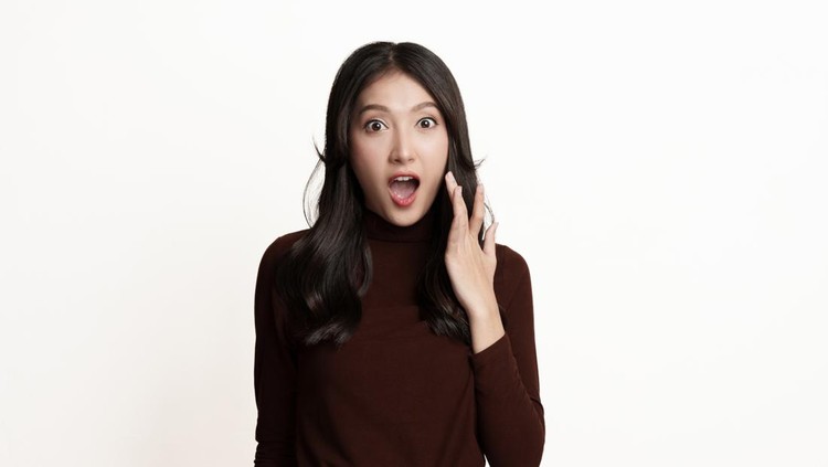 1387633632 Portrait of beautiful young Asian woman showing expression of surprise on white background. Excited girl looking at camera and gasping.