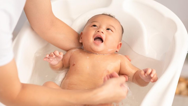 Calm of asian newborn baby bathing in bathtub.mother bathing her son in warm water.Happy adorable newborn infant smile in tub relax and comfortable.Newborn baby care concept