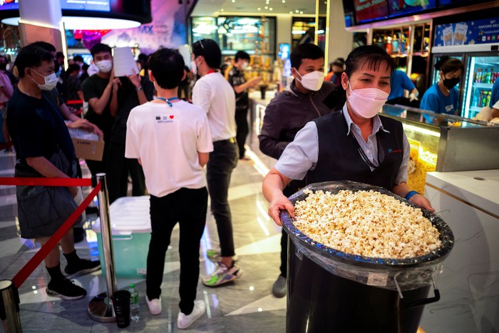 People carry steel vats, cardboard boxes and plastic storage containers as they queue during a campaign 