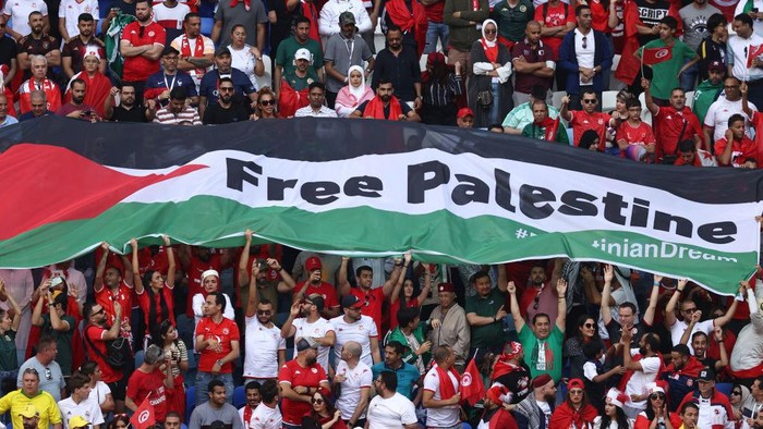 AL WAKRAH, QATAR - NOVEMBER 26:  Fans hold a Flag of Palestine with Free Palestine written on it during the FIFA World Cup Qatar 2022 Group D match between Tunisia and Australia at Al Janoub Stadium on November 26, 2022 in Al Wakrah, Qatar. (Photo by James Williamson - AMA/Getty Images)