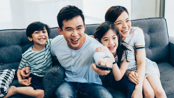 Cheerful asian family relaxing at home watching tv