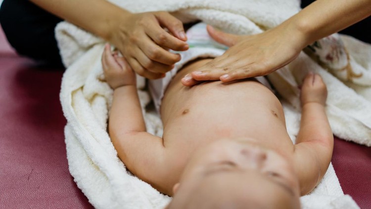 Ilustrasi Teknik Memijat Bayi Image of an Asian Chinese woman applying baby cream and massaging her baby boy after bath