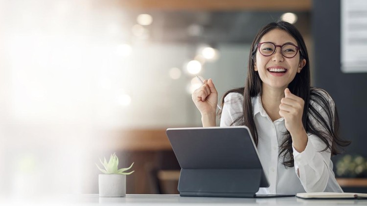 Elegant businesswoman sitting in office with digital tablet. Excited asian businesswoman raising hands to congratulate while working on laptop in office.