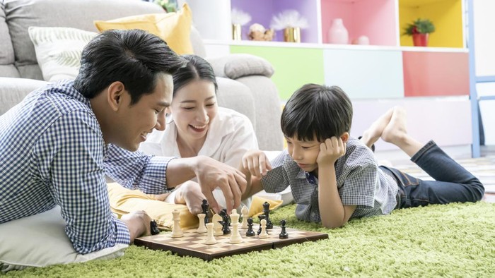 Time with loved one concept, Happy Asian family playing chess game in the living room together.