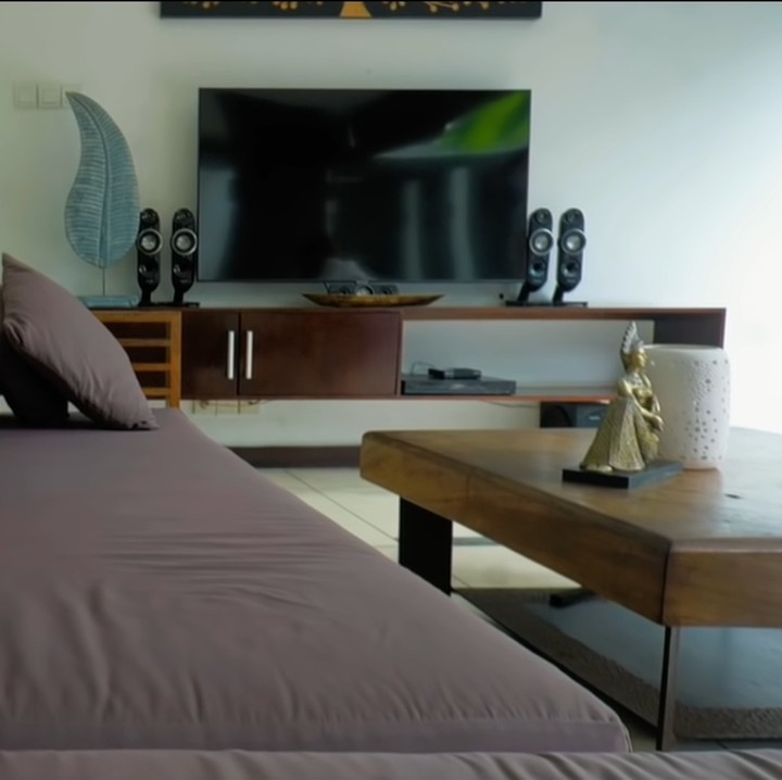 <p>Dari kolam renang, terdapat living area yang didominasi sofa dan furnitur lain berwarna cokelat. Seperti villa di Bali lainnya, luvung area villa Rossa berkonsep terbuka yang memanfaatkan sirkulasi udara alami. (Foto: YouTube/Rossa Official)</p>