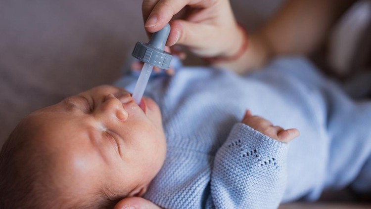 Woman feeding newborn baby via pipette