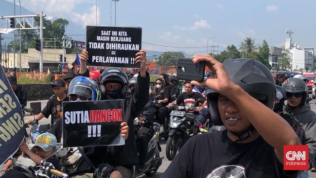 Suporter Arema FC, Aremania melumpuhkan lalu lintas di Jalan Malang Raya selama 135 menit lewat aksi diam menagih penuntasan kasus Kanjuruhan.