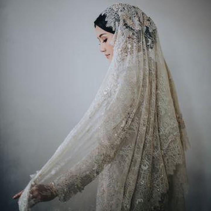 <p>Erina Gudono tampil mengenakan busana warna putih karya Artkea pada pagi hari. Tak hanya itu, ia juga memakai rancangan busana Wiranti Kurnia Bride untuk pengajian sore. Busana Erina dilengkapi dengan tudung atau veil yang menghiasi kepalanya. (Foto: Dok. Bride Story)</p>