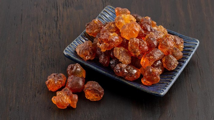 a group of dried peach gum in dish on wood background