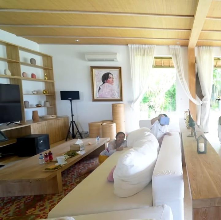 <p>Tidak hanya itu, setiap sisi rumahnya kebanyakan didominasi oleh warna putih dan aksen kayu, Bunda. Ini adalah potret ruang keluarganya yang baru dilengkapi televisi, meja, dan beberapa sofa. (Foto: YouTube maharani kemala)</p>
