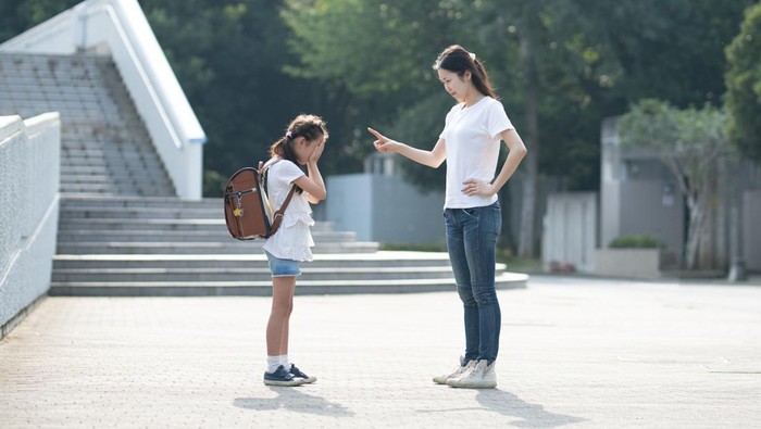 A woman scolding an elementary school student