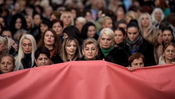 Serb women stand behind a flag as they protest following a governments' dispute between Kosovo and Serbia, in the Serb pre-dominant part of Mitrovica in Kosovo, on November 23, 2022. - The government in Pristina declared in November that around 10,000 Kosovo Serbs with licence plates issued by Serbia must replace them by April 2023 with plates issued by the Republic of Kosovo according to a gradual plan involving warnings, fines and eventually road bans. (Photo by Armend NIMANI / AFP)