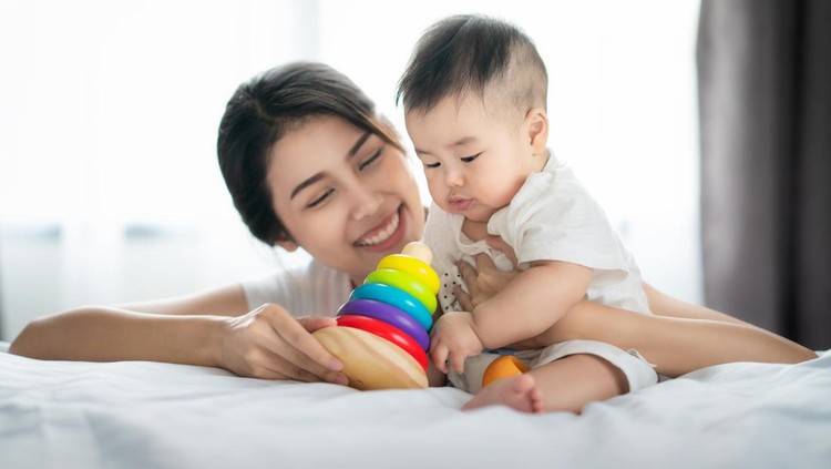 Asian mother play with her baby in bed room, this picture can use for education, study, mother, mom and toy concept