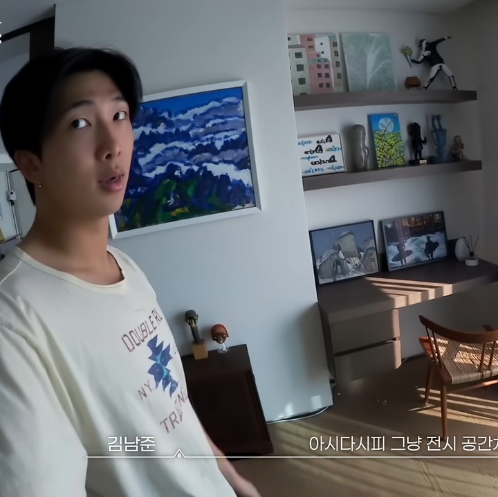 <p>Pria bernama asli Kim Nam-joon ini memang terkenal memiliki hobi koleksi lukisan setelah membaca buku. Di meja kerjanya pun berjejer beberapa lukisan yang ia pajang. (Foto: YouTube/BANGTAN TV)</p>