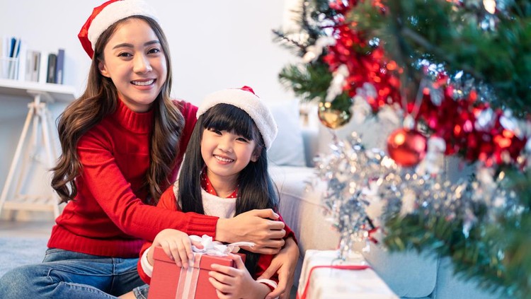 Portrait of Asian young little young daughter open gift box from mom. Happy family, little kid feel happy and excited for surprise from mother ready to celebrate Christmas together and look at camera.