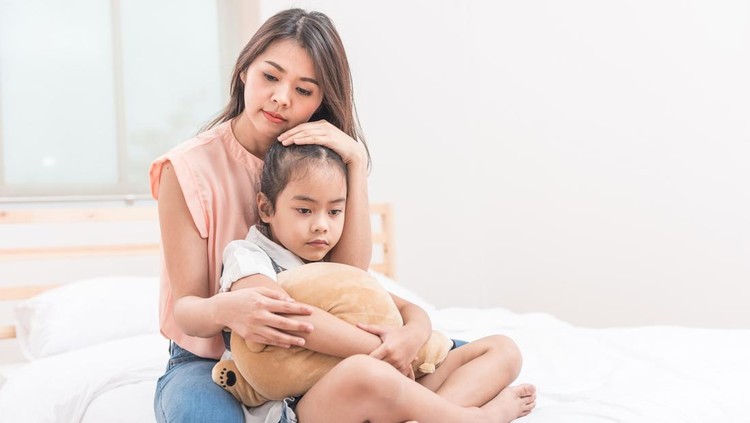 Asian mother hugging and comforting her sad daughter in bed room