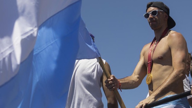 Emiliano Martinez gendong 'bayi Mbappe' dan Messi tersenyum saat parade perayaan Argentina juara Piala Dunia 2022 di Buenos Aires, Selasa (20/12).