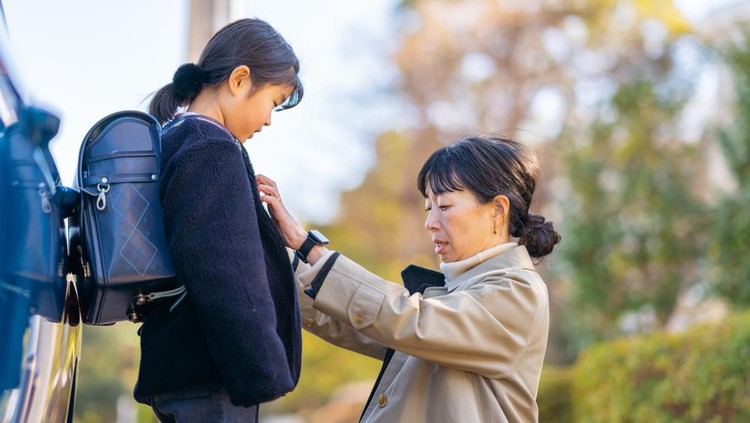 A working business mother is taking her daughter to school with a car while she is commuting to work.