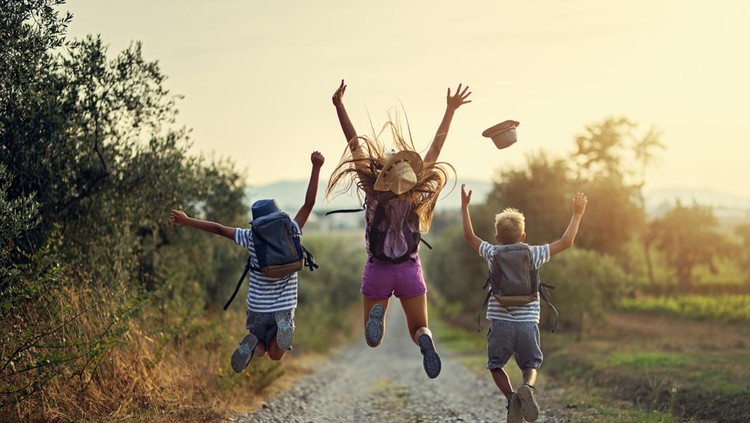 Brothers and sister hiking in Tuscany, Italy. Kids are jumping with joy on dirt road.

Nikon D850