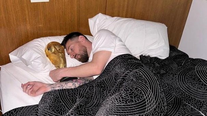 Argentina's Lionel Messi lies in bed with the FIFA World Cup trophy, at an unknown location, in this screenshot taken from social media and released on December 20, 2022. Instagram/leomessi/via REUTERS  THIS IMAGE HAS BEEN SUPPLIED BY A THIRD PARTY. MANDATORY CREDIT. NO RESALES. NO ARCHIVES.