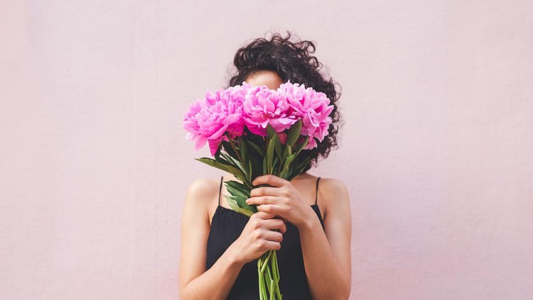 Cropped shot of a woman holding a bouquet of flowers in front of her face
