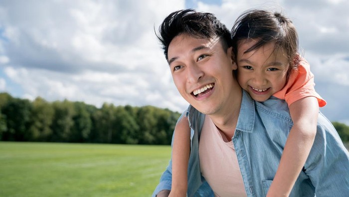 Cute Chinese girl crying on her father’s shoulder.