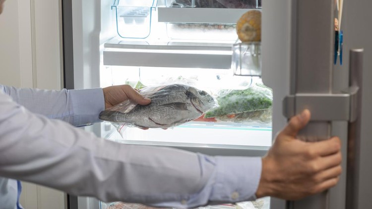 A man taking a fish into fridge.