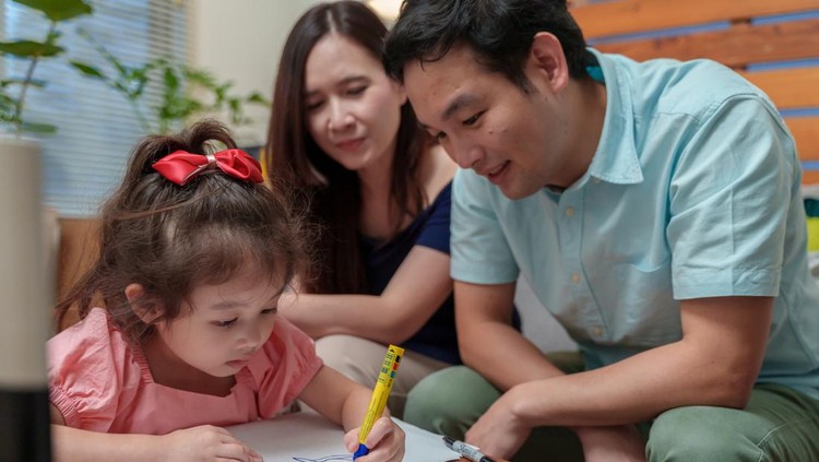 Asian little cute girl drawing and writing Christmas cards, preparing for celebrating Christmas and New year. Adorable girl focusing on her draws while making Christmas cards with her parents.