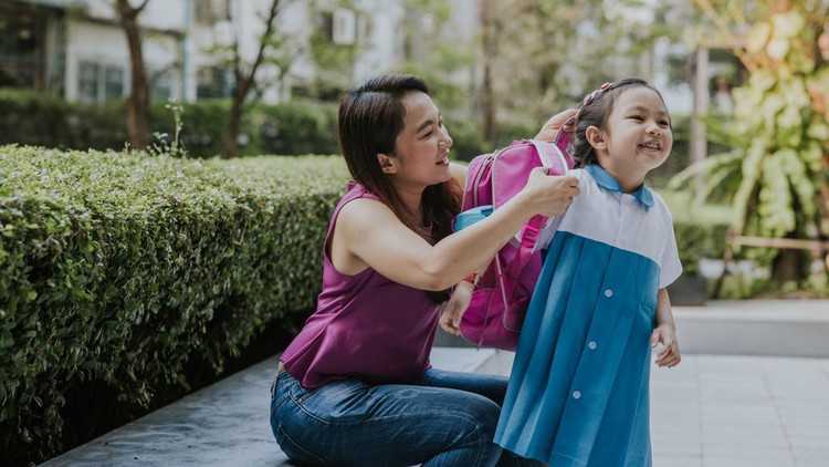 Ilustrasi Jadwal Masuk Sekolah 38 Provinsi Thai daughter holding her school bag while mother supporting at garden before go to school, Thailand