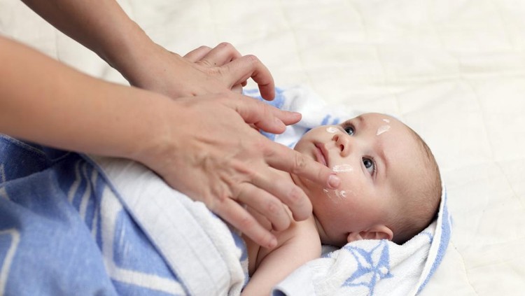 Baby with atopic dermatitis getting cream put. Care and Prevention Of Eczema. Keep Your Baby From Itching