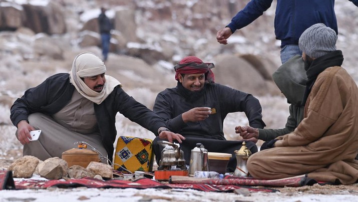 Warga Saudi mencairkan salju untuk membuat kopi di Jabal al-Lawz (Gunung Almond), sebelah barat kota Tabuk di Saudi pada 17 Januari 2022. (IBRAHIM ASSIRI/AFP via Getty Images)