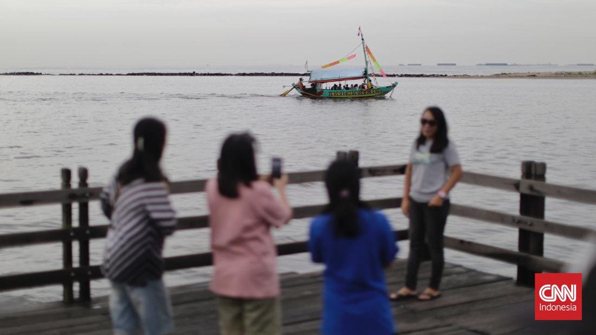 FOTO: Tertutup Awan Mendung, Pantai Ancol Tetap Ramai Pengunjung