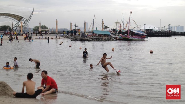 FOTO: Tertutup Awan Mendung, Pantai Ancol Tetap Ramai Pengunjung