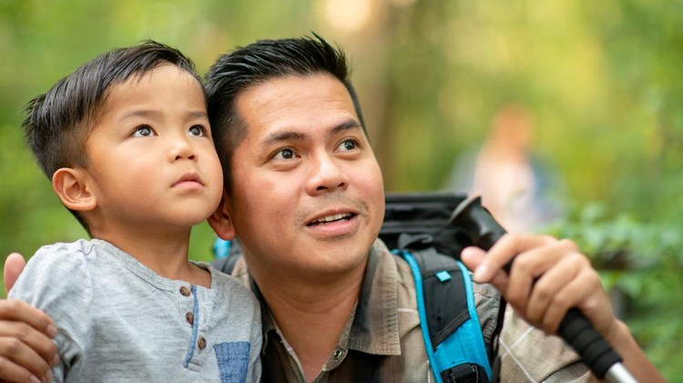 Ilustrasi Dampak Anak Laki-laki Tanpa Ayah A Filipino father and son take a hike in the woods birdwatching. The father has crouched down low to the young boy as they both look to the trees at the birds.